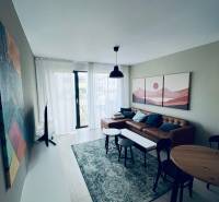 Wohnzimmer in einer 2-Zimmer-Wohnung mit Ledersofa, rundem Tisch und dekorativen Bildern.