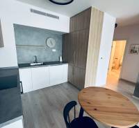 Küche in einer 2-Zimmer-Wohnung mit Holztisch und schwarzen Stühlen.