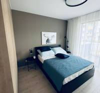 Schlafzimmer in einer 2-Zimmer-Wohnung mit Bett, Nachttischen und einem Bild an der Wand.