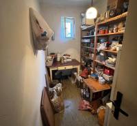 Lagerraum in einem Einfamilienhaus mit Regalen voller verschiedener Gegenstände und offenem Fenster.