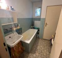 Ein Badezimmer in einem Einfamilienhaus mit einer alten Badewanne, einem Waschbecken und Fliesen.