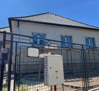 Ein Einfamilienhaus in Sasinkovo in der Sasinkovo-Straße mit unvollendeter Fassade hinter einem Metallzaun.