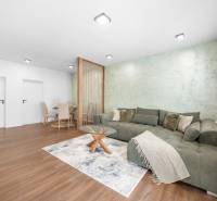 Wohnzimmer in einer 3-Zimmer-Wohnung mit Sofa, Esstisch und Holzboden.
