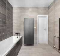 Badezimmer mit Badewanne, grauen Fliesen und schwarzen Accessoires in einer 3-Zimmer-Wohnung.