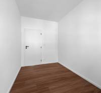 Ein leerer Raum mit weißen Wänden und Holzboden in einer 3-Zimmer-Wohnung.