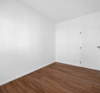 Ein leerer Raum mit Holzboden und weißen Wänden in einer 3-Zimmer-Wohnung.