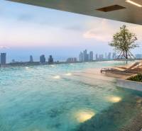 Ein Pool mit Liegestühlen und Blick auf die Skyline von Pattaya, Wohnungsbau.