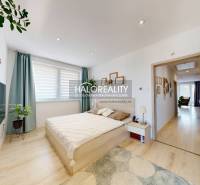 Schlafzimmer in einer 3-Zimmer-Wohnung mit Bett, Fernseher und Pflanzen, hellem Interieur.