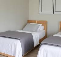 Zwei Einzelbetten mit grauen Decken in einer 3-Zimmer-Wohnung.