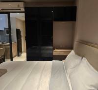 Schlafzimmer mit weißem Bett und schwarzem Schrank, neben der Küchenzeile.