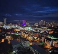 Nächtlicher Blick auf die Stadt Pattaya mit beleuchteten Gebäuden und Silhouetten am Horizont.