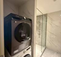 Badezimmer in einer 3-Zimmer-Wohnung mit Waschmaschine und Trockner neben der Duschkabine.