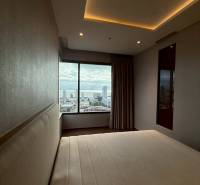 Schlafzimmer in einer 3-Zimmer-Wohnung mit Blick auf die Stadt durch ein großes Fenster.