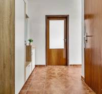 Flur mit braunen Türen und Fliesen in einer Einzimmerwohnung mit Kleiderhaken.