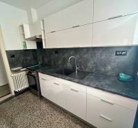Küche mit weißen Schränken und grauer Arbeitsplatte in einer 3-Zimmer-Wohnung.