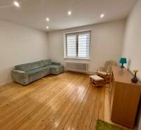 Wohnzimmer mit Holzboden, grauem Sofa und Sessel in einer 3-Zimmer-Wohnung.
