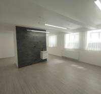 Geschäftsräume mit Holzboden und Wand, vertikale Jalousien an den Fenstern.
