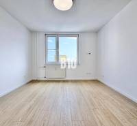 Helles Zimmer mit Holzboden und großem Fenster in einer 3-Zimmer-Wohnung.