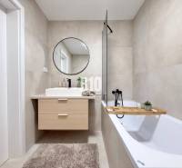 Ein Badezimmer in einer 3-Zimmer-Wohnung mit Badewanne, Spiegel und Holzzubehör.