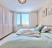 Helles Schlafzimmer in einer 3-Zimmer-Wohnung mit großem Bett, Schrank und dekorativen Bildern.