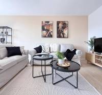 Helles Wohnzimmer mit Sofas, dekorativen Bildern und einem Tisch in einer 3-Zimmer-Wohnung.