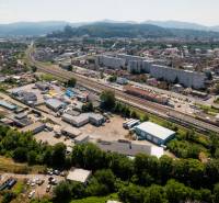 Luftaufnahme von Trenčín, Kasárenská-Straße und Lagerhallen, im Hintergrund Berge.