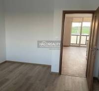 Ein Zimmer mit weißen Wänden und Türen zu einem hellen Raum in einer Zweizimmerwohnung.
