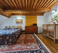 Schlafzimmer in einem Einfamilienhaus mit Holzdecke, Bett, Kinderbett und Teppich.