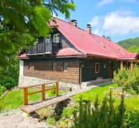 Ein Einfamilienhaus in Donovaly mit einer Holzfassade und einem roten Dach in einer natürlichen Umgebung.