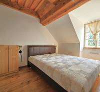 Ein Schlafzimmer im Dachgeschoss eines Einfamilienhauses mit Dachbalken und einem großen Fenster.