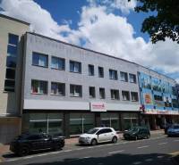 Geschäftsräume in der 1. mája Straße in Poprad mit Autos, die vor dem Gebäude geparkt sind.
