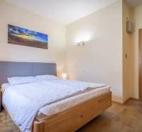 Helles Schlafzimmer des Ferienapartments mit Doppelbett, Nachttischen und Wanddekoration.