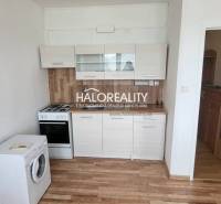 Küche in einer Einzimmerwohnung mit Herd, Geschirrspüler und Schränken, Holzboden.