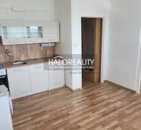 Küchenzeile in einer Einzimmerwohnung mit Holzboden und weißen Schränken.