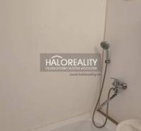 Badezimmer mit Badewanne und Dusche in einem Einzimmerapartment, klare Linien und praktische Anordnung.