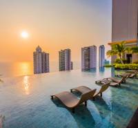 Schwimmbad, Liegestühle und Panorama des Wohnungsbaus in Pattaya bei Sonnenuntergang.