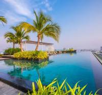 Infinity-Pool und Palmen auf dem Dach mit Blick auf die Skyline von Pattaya, Wohnungsbau.