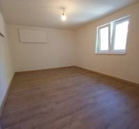Ein leerer Raum mit Laminatboden und weißen Wänden in einem Einfamilienhaus.