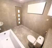 Badezimmer im Einfamilienhaus mit Badewanne, Waschbecken und Toilette, helle Fliesen.