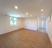 Geräumiges Wohnzimmer in einem Einfamilienhaus mit Holzboden und weißen Wänden.