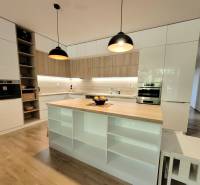 Küche in einer 3-Zimmer-Wohnung mit Insel, Holzelementen und eingebauten Geräten.