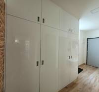 Eingangsflur in einer 3-Zimmer-Wohnung mit weißen Schränken und Ziegelverkleidung.
