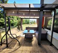 Die Terrasse einer 3-Zimmer-Wohnung in Banská Bystrica mit einer Schaukel und einem Tisch zum Sitzen.