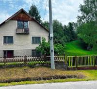 Ein Einfamilienhaus in Veľká Lesná mit gepflegtem Garten und Rasen, umgeben von Bäumen.