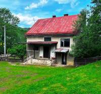 Ein Einfamilienhaus in Veľká Lesná mit rotem Dach und einem Garten, umgeben von Grün.