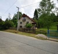 Ein Einfamilienhaus in Veľká Lesná an der Straße, umgeben von Grün und einem Zaun.
