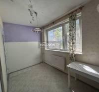 Ein Zimmer in einer Einzimmerwohnung mit einer lila Wand und einem weißen Tisch unter dem Fenster.