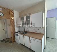 Küche in einer Einzimmerwohnung mit Gasherd und Schränken an der weißen Wand.