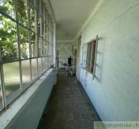 Eine verglaste Veranda in einem Einfamilienhaus mit Blick auf den Garten und Möbeln.