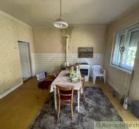 Küche in einem Einfamilienhaus mit Esstisch, älterem Herd und einfacher Einrichtung.